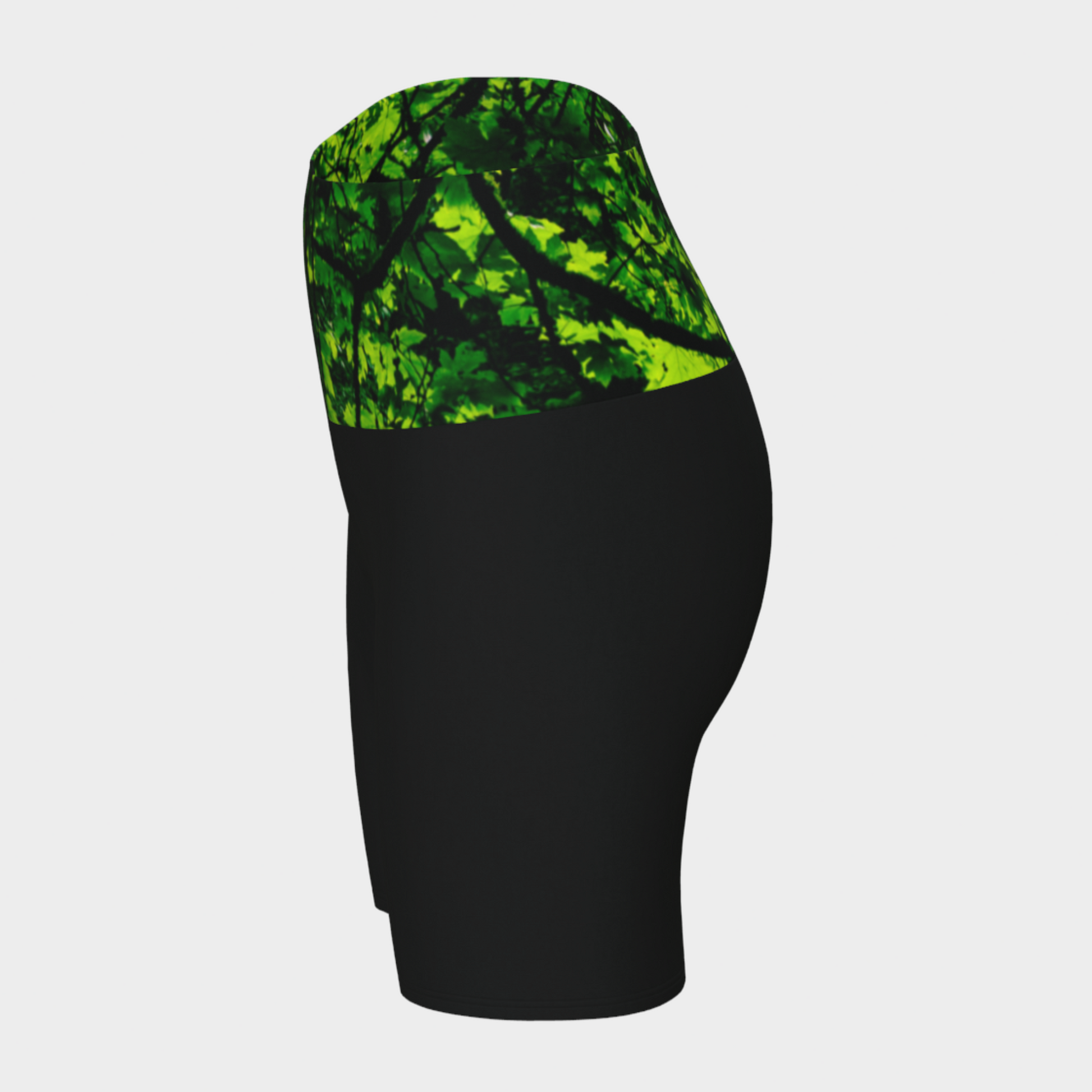 Side Veiw Canopy of Leaves yoga shorts.  The high waist band features a canopy of leaves printed on it.  the bottom portion of the shorts are black.