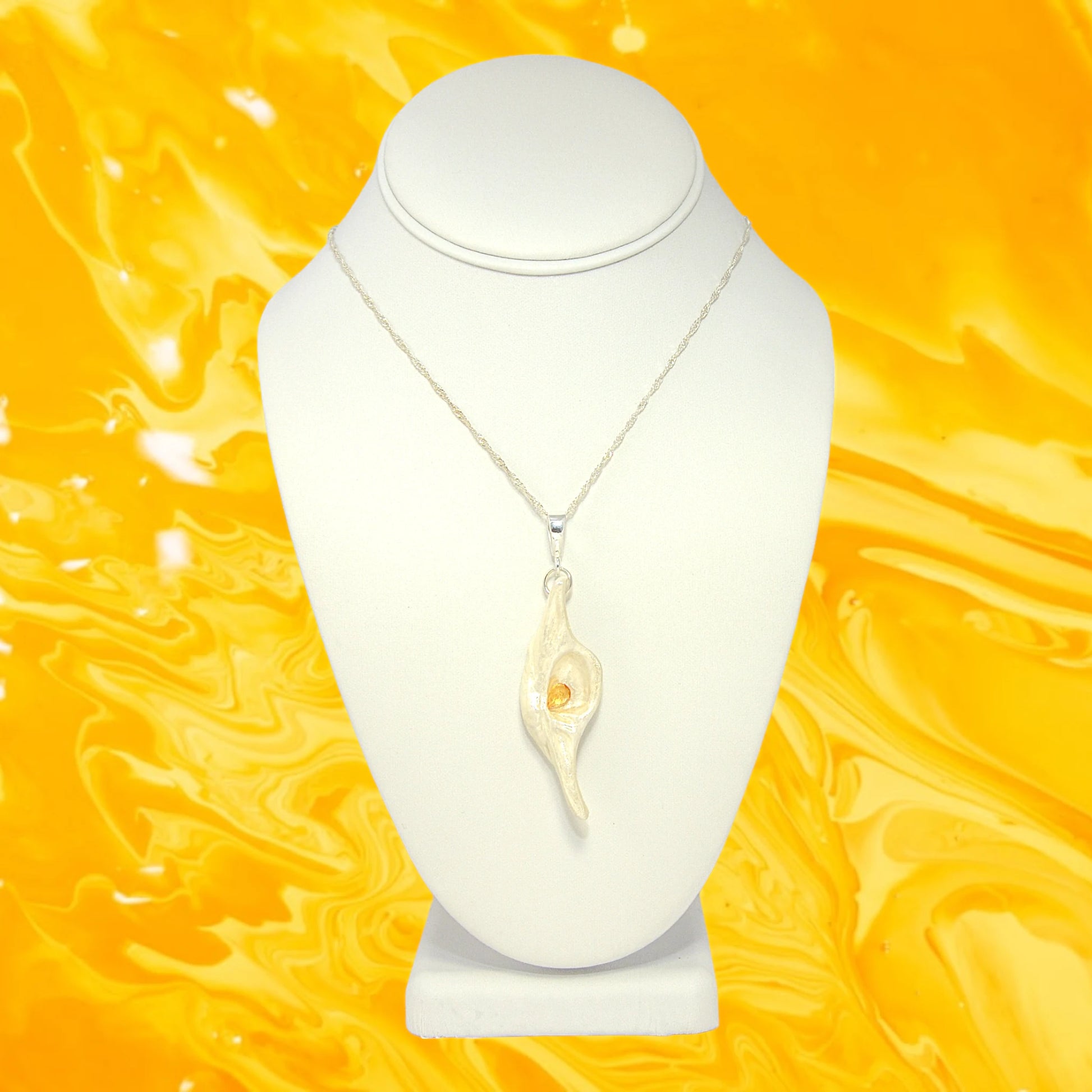 Lightmaker natural seashell pendant A beautiful pear shaped rose cut Citrine compliments the pendant. the pendant is shown hanging on a white necklace displayer with a yellow background,