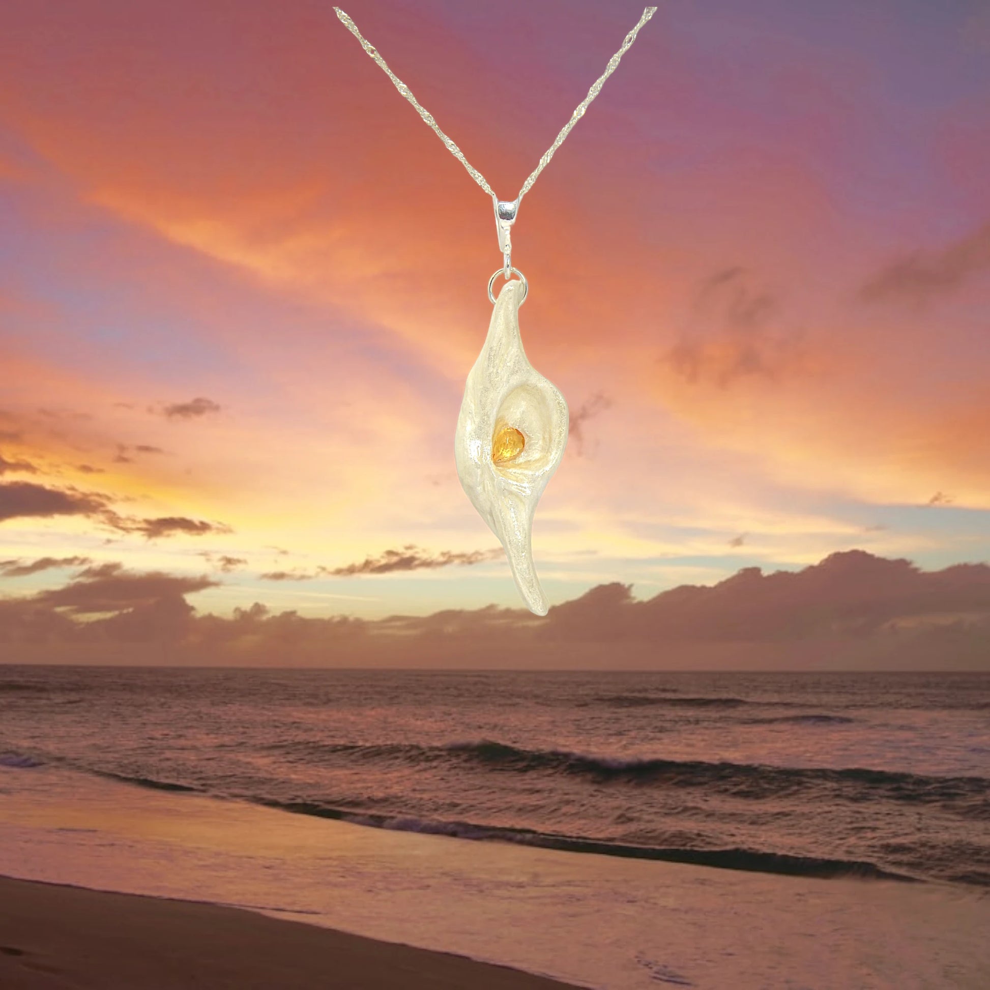 Lightmaker natural seashell pendant A beautiful pear shaped rose cut Citrine compliments the pendant. The background shows the sunset over the ocean.