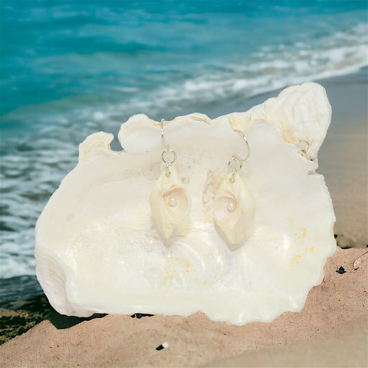 Serenity natural seashell earrings with real baby freshwater pearls. The ocean is in the background.